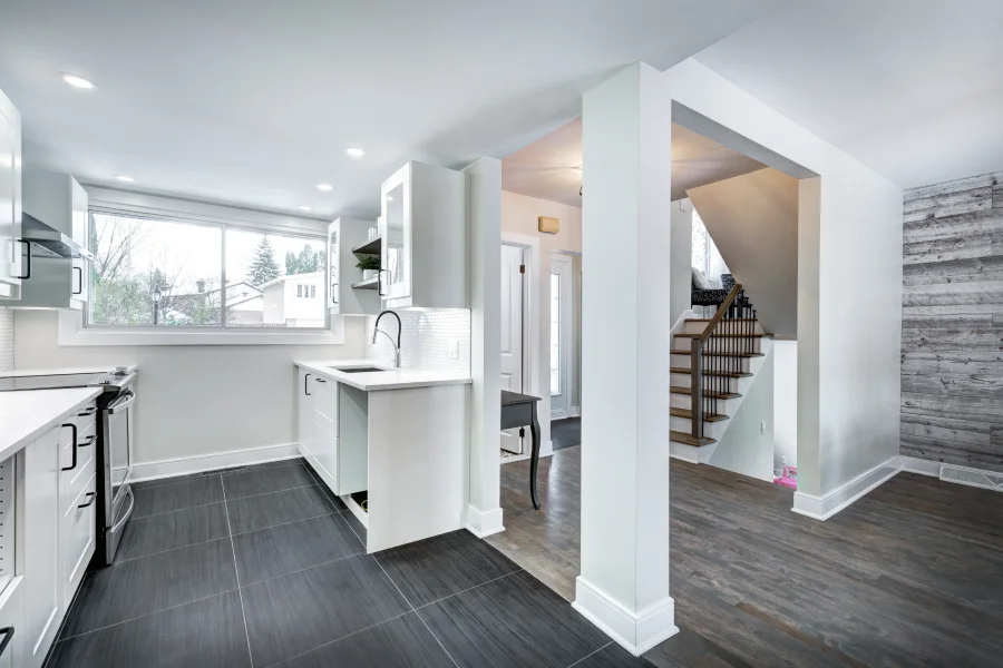 A modern kitchen featuring white cabinets and a warm wooden accent wall.