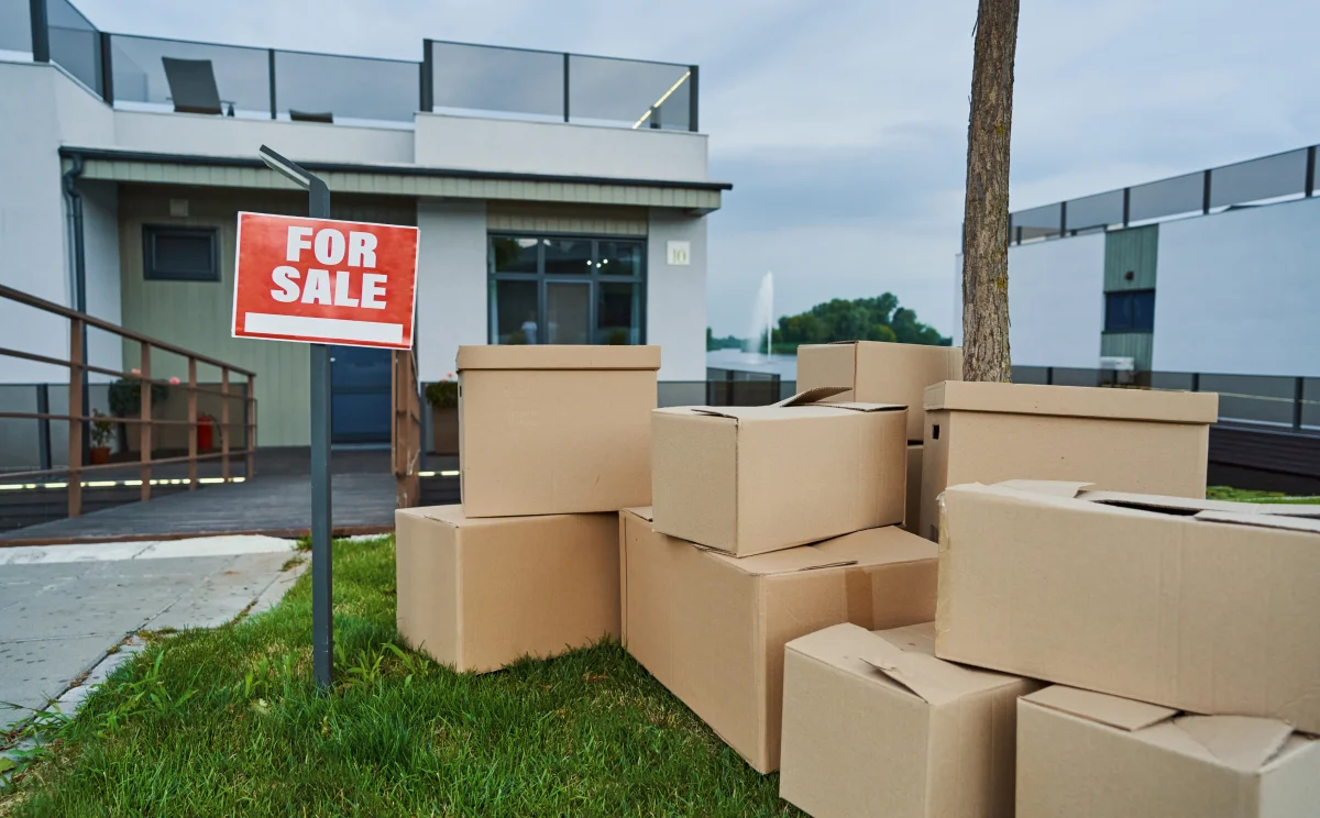 A stack of cardboard boxes is placed in front of a house, indicating a recent move or delivery.